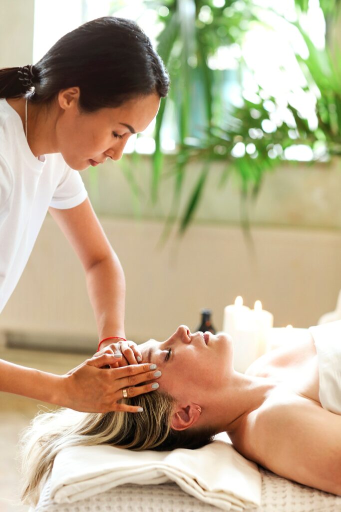 Asian masseuse massaging face of client