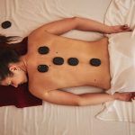 Hot massage stones covering shoulder blades and spine of female